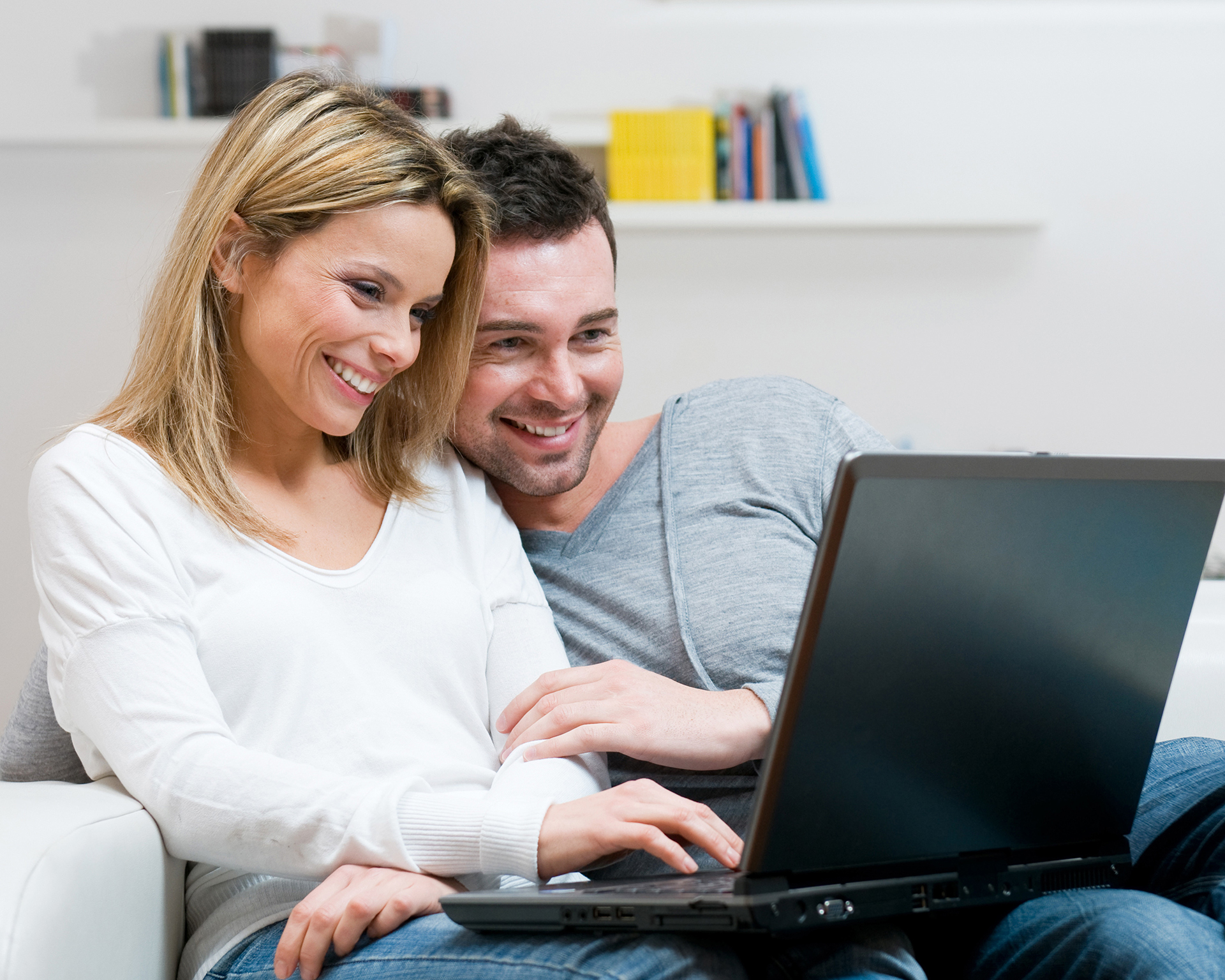Ein Paar sitzt auf der Couch und sehen sich am Computer WEKA Angebote an