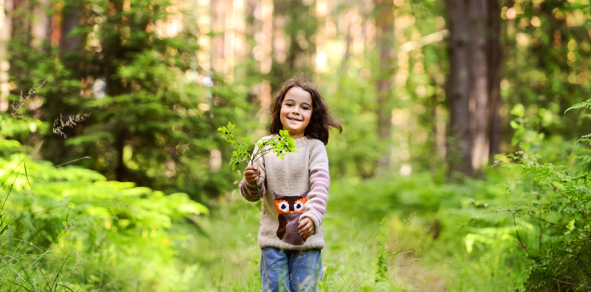 Ein Kind geht mit einer Pflanze in der Hand im Wald spazieren