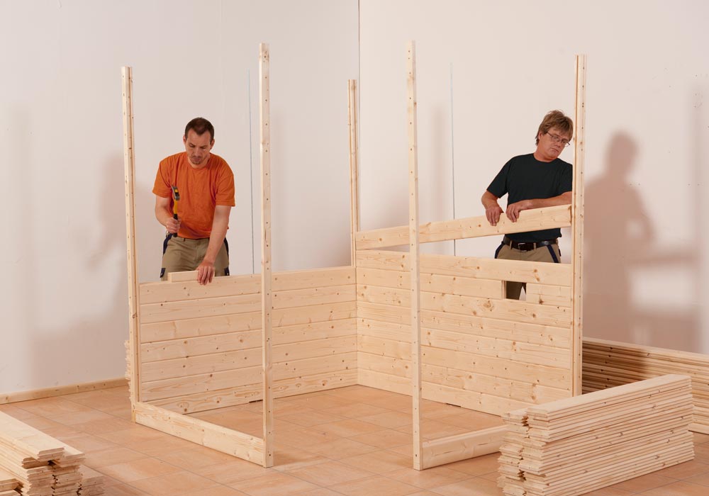 Zwei Männer bauen eine Sauna für den Innenbereich auf