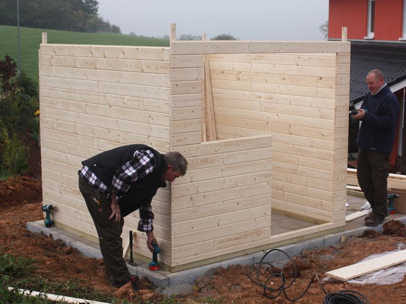 Zwei Männer bauen ein Gartenhaus auf