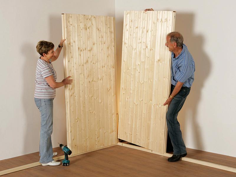 Mann und Frau montieren zwei Wandelemente einer Sauna zu einer Ecke