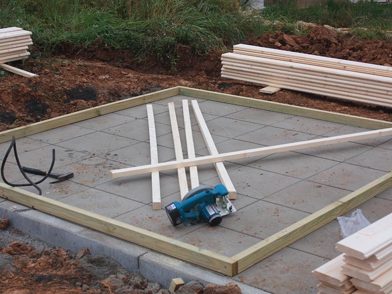 Vorbereitung der Bodenbalken auf dem Fundament für den Aufbau eines Gartenhauses