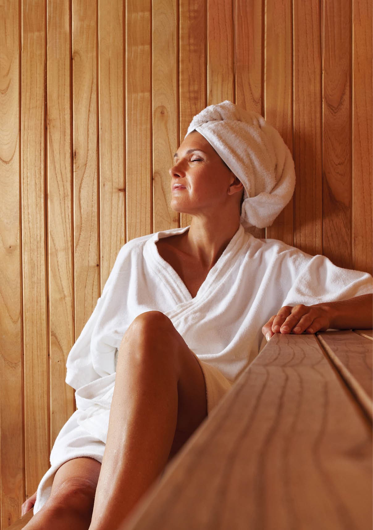  ltere Frau sitzt entspannt in einer Sauna aus Holz